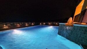 A nighttime swimming pool with illuminated edges, a stone wall, and a water fountain. - SOPHISTICATED BEACHFRONT RETREAT -  New Furniture & Decor!! (Orange Beach)