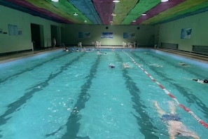 A swimming pool with lanes, a diving board, and a ceiling with colorful patterns. - Jincheng Hot Spring Hotel (Zhaoyuan)