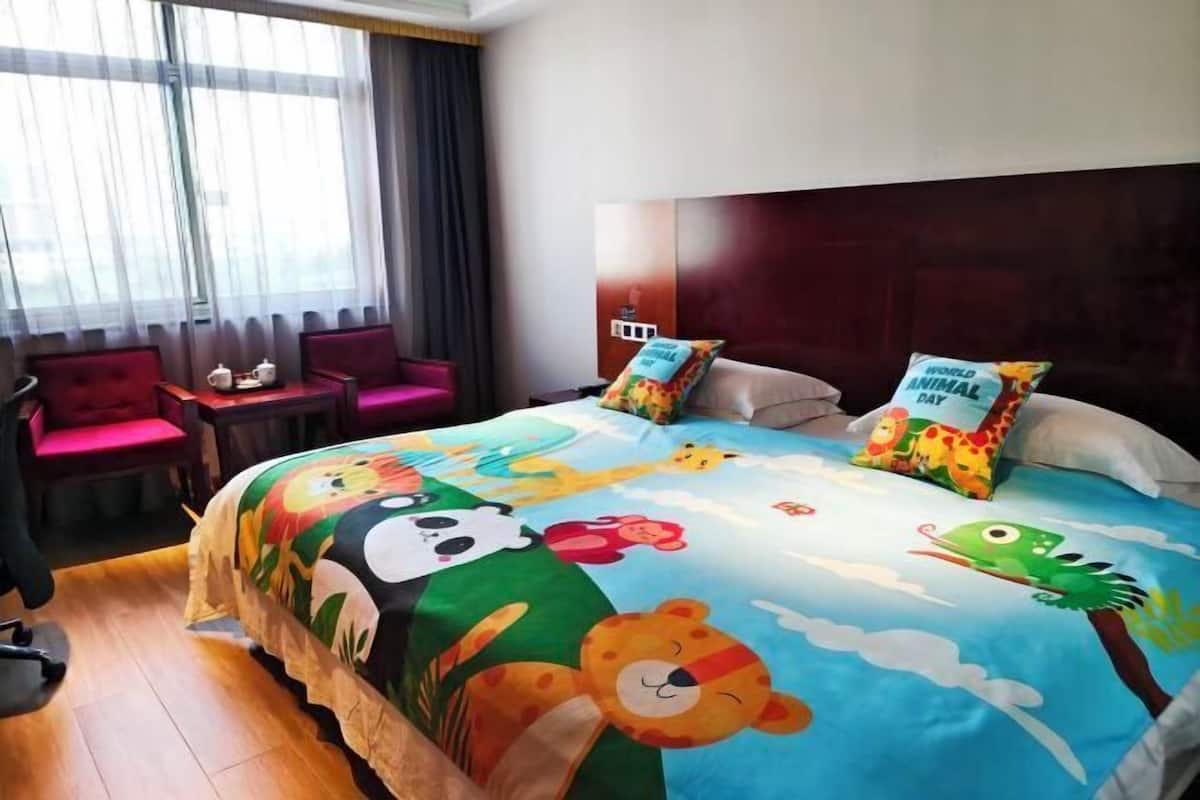A hotel room with a bed, a desk, a chair, and a window with curtains.