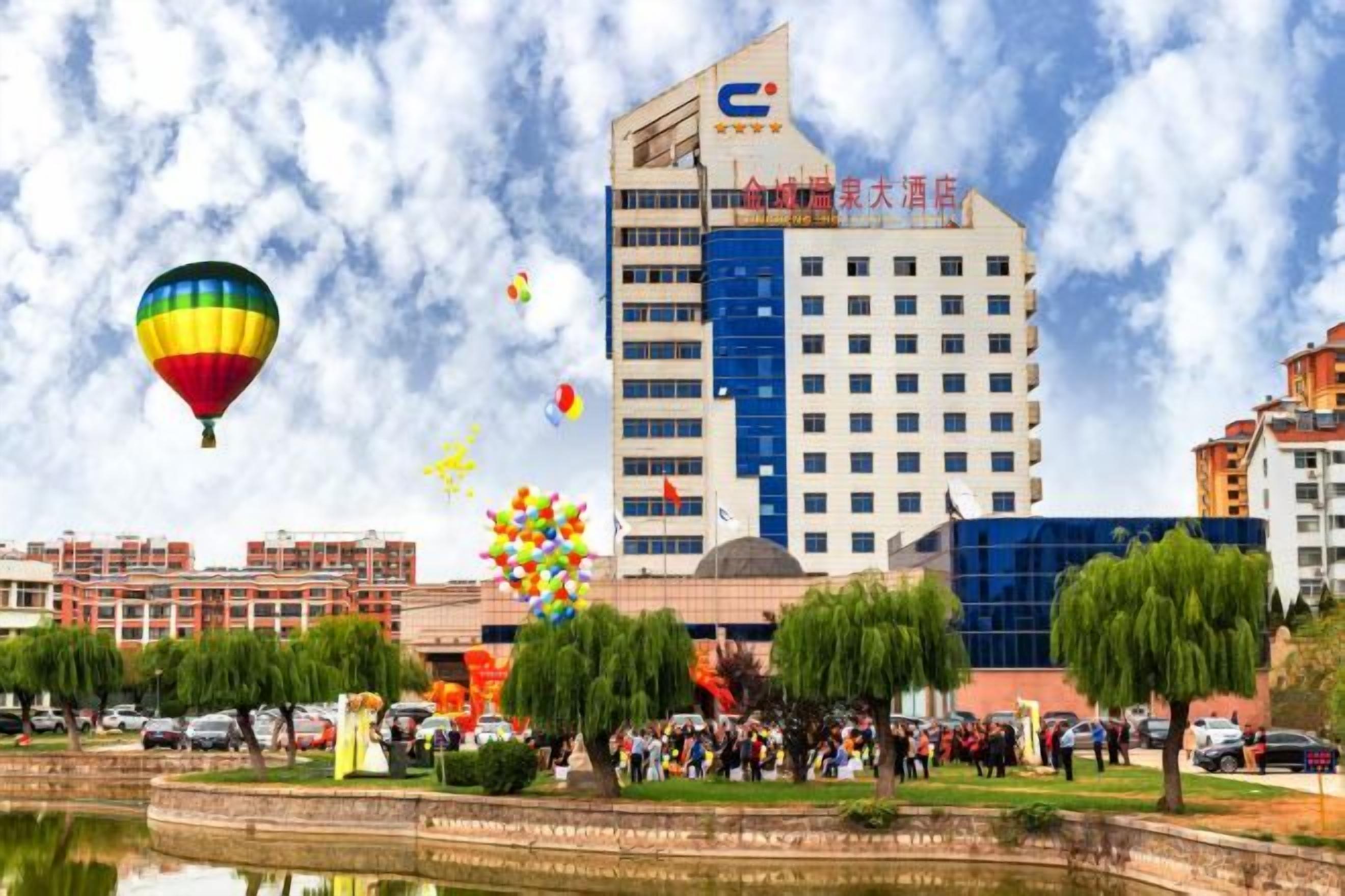 A hotel with a modern design, a large building, and a surrounding park with trees and a pond.