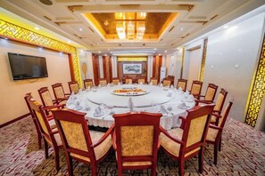 A conference room with a round table, chairs, and a television screen.