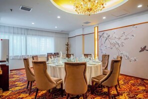 A conference room with a round table, chairs, and a chandelier.