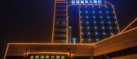 L'hôtel Jincheng Hot Spring, reconnaissable à son enseigne bien visible et à sa façade illuminée la nuit.