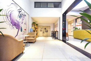 A modern interior with a sofa, a coffee table, a painting, and a yellow reception desk.