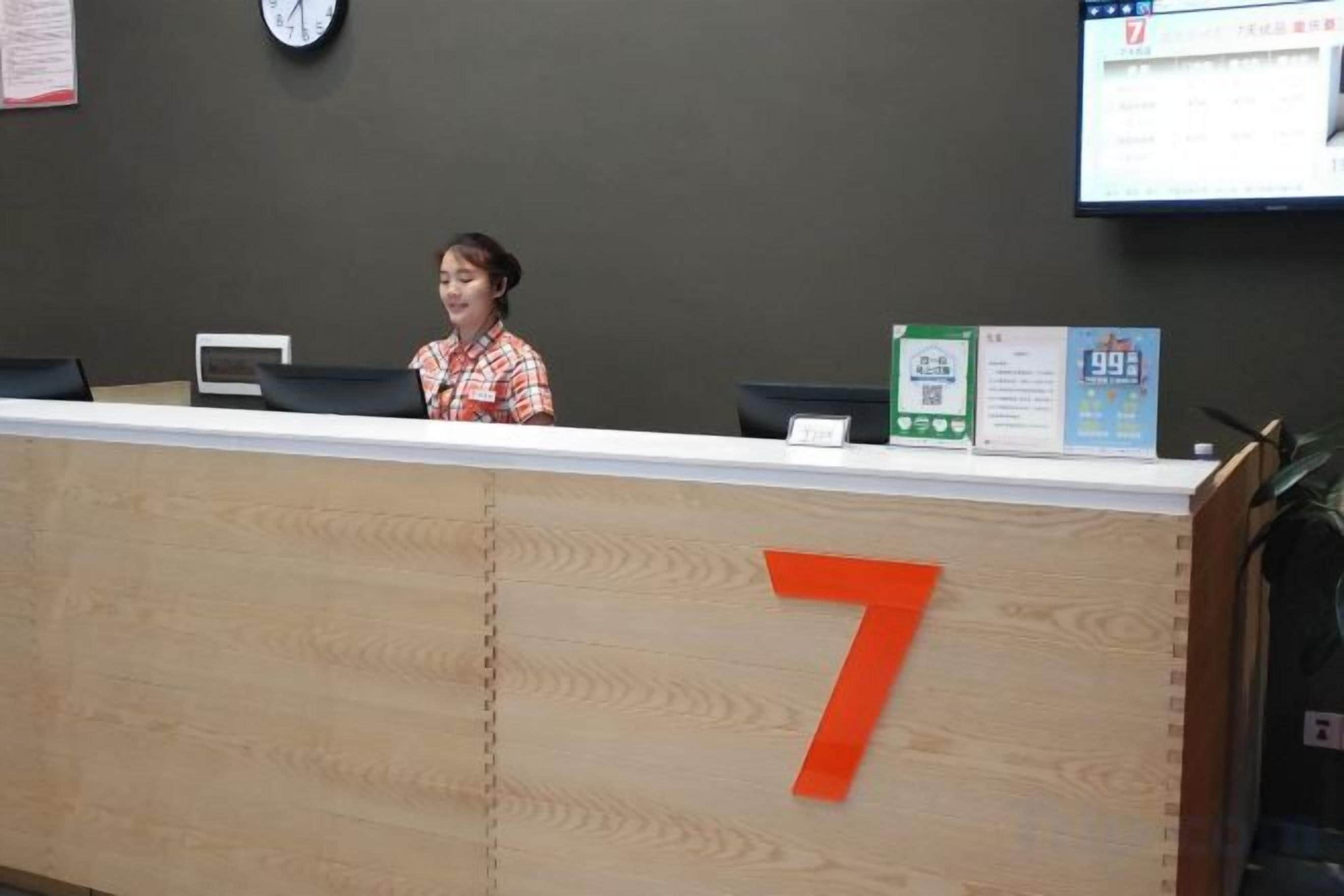 A reception desk with a number 7 sign, a clock, and a computer monitor on the wall.