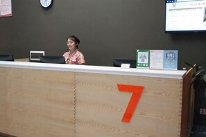 A reception desk with a number 7 sign, a clock, and a computer monitor on the wall. - 7 Days Premium. Chongqing Qijiang District Government Store (Chongqing)