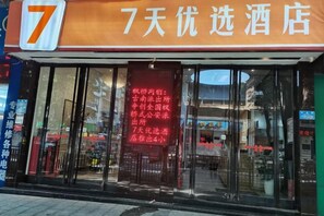 A hotel entrance with a large number '7' sign above the door, a red banner with white text, and a glass facade. - 7 Days Premium. Chongqing Qijiang District Government Store (Chongqing)