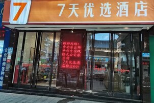Entrada de un hotel con un gran letrero con el número 7 sobre la puerta, un banderín rojo con texto blanco y fachada de vidrio.