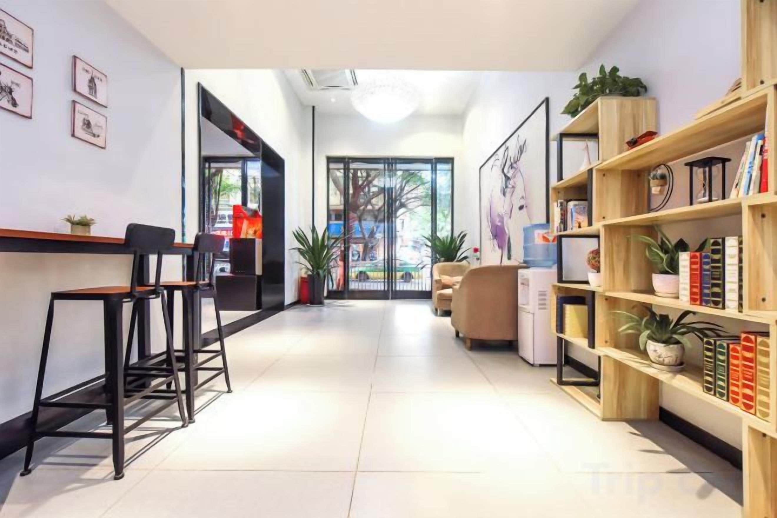 Un vestíbulo de hotel con mostrador de recepción, zona de estar y estanterías.
