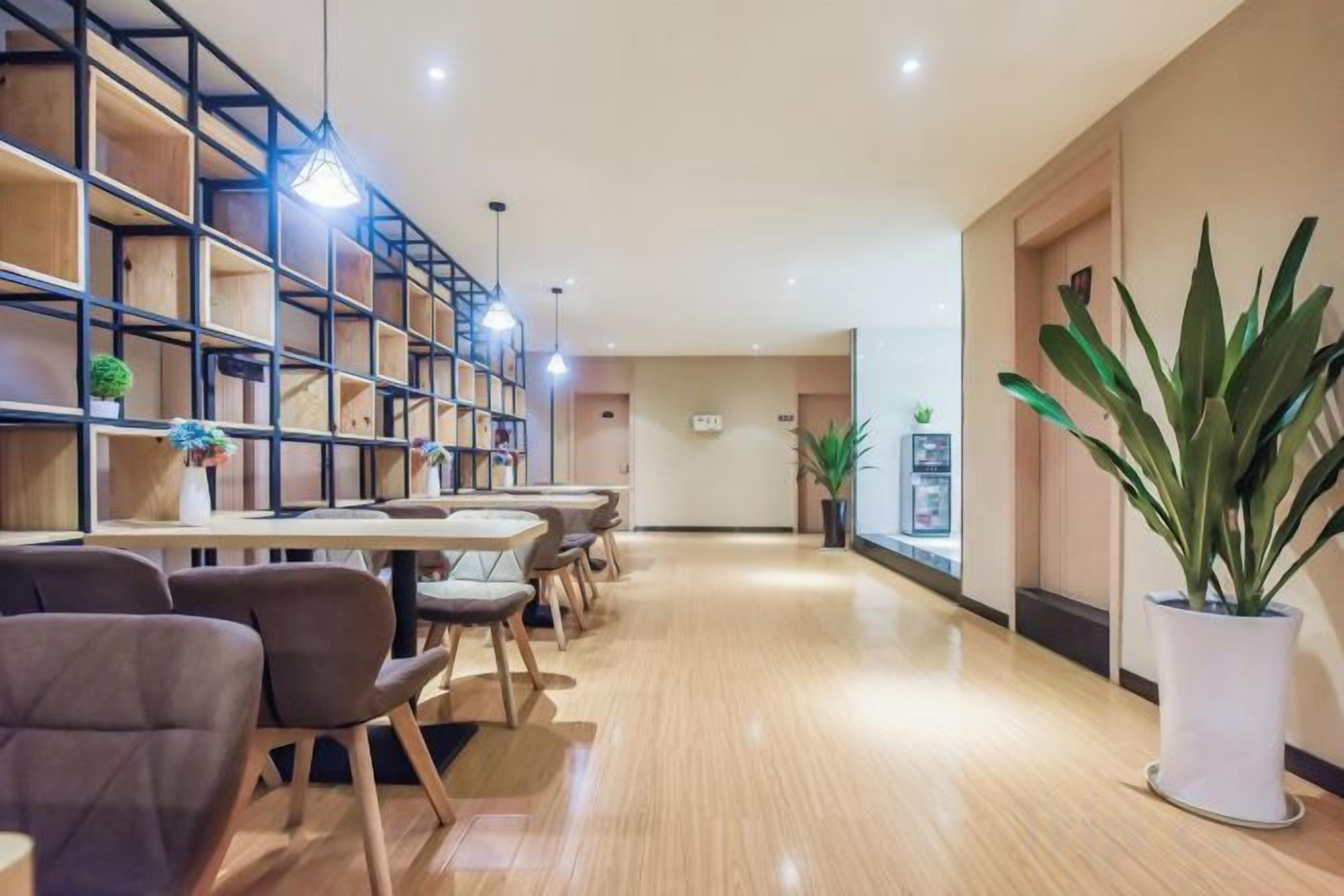 A hotel lobby with a long reception desk, seating area, and a bookshelf.