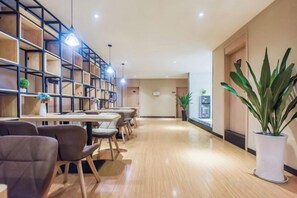 Un hall d’hôtel avec un long comptoir d’accueil, un espace salon et une bibliothèque.