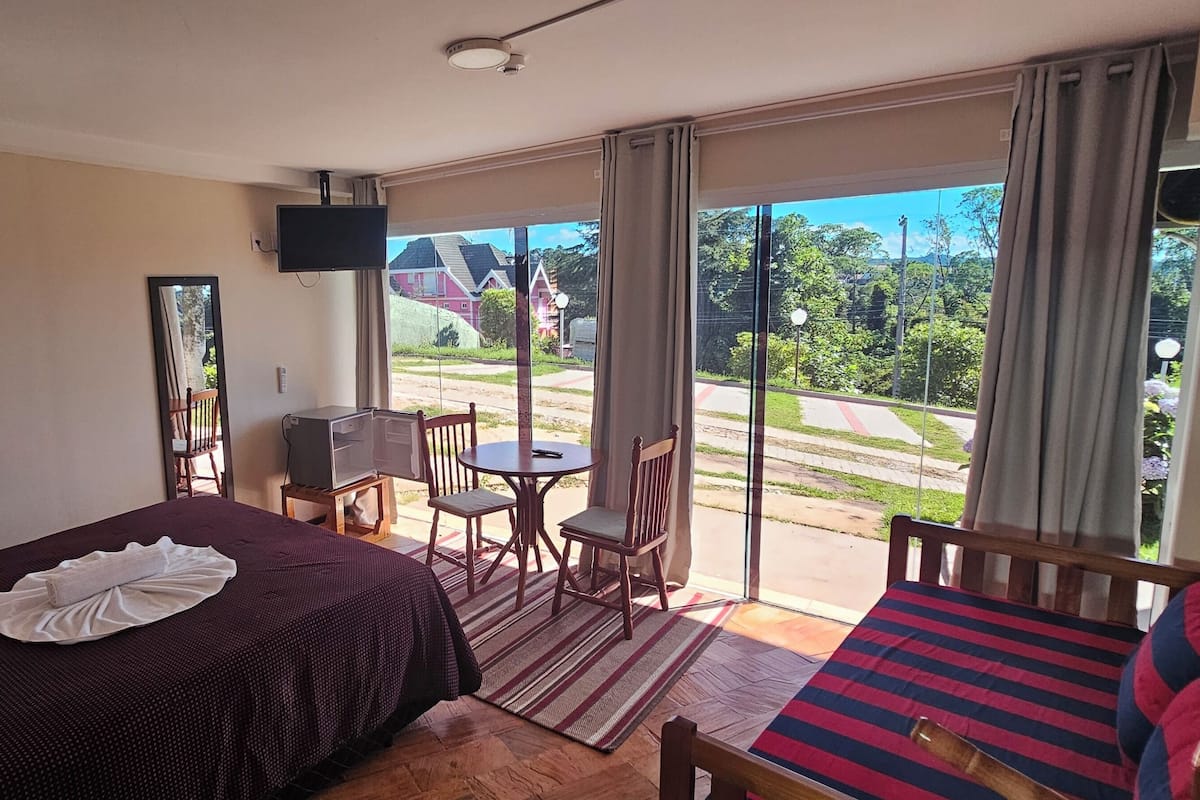 Una habitación de hotel con una cama, televisor, una mesita y una silla.