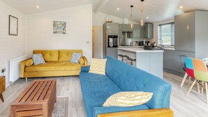 Un salon moderne avec un canapé jaune et un canapé bleu, une table basse en bois et un fauteuil coloré.