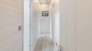Un couloir étroit aux murs en bois peints en blanc et au plancher en bois.