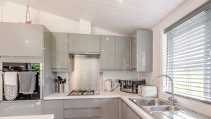 Une cuisine moderne avec des meubles gris, une cuisinière à gaz, un grille-pain et un évier.