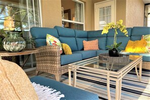 A cozy living area with a blue sofa, wicker chair, and a glass coffee table. - Sunset Rays Escape! (Cape Coral)