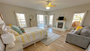 A spacious bedroom with a bed, a grey sofa, a fireplace, and a balcony. - Peaceful property on the historic Suwannee River. (Bell)