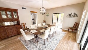 A dining room with a large wooden table, white upholstered chairs, a patterned rug, and a chandelier. - Peaceful property on the historic Suwannee River. (Bell)