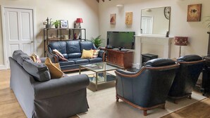 A living room with a sofa, armchairs, a coffee table, a TV, and a fireplace. - Soft sandy beach, award winning pub a short distance. (Ingham)