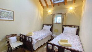 A bedroom with two single beds, a wooden chair, a small table, and a map on the wall. - Soft sandy beach, award winning pub a short distance. (Ingham)