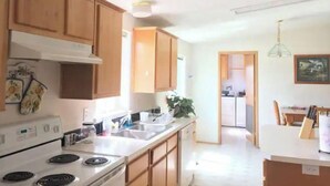 Cuina amb armaris de fusta, una cuina blanca i un rentamops.