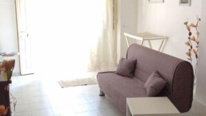 Una sala de estar con sofá, una mesita y una puerta que da al exterior.