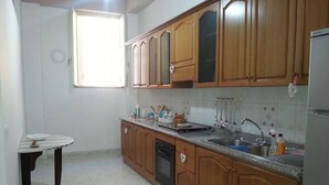 Una cocina con armarios de madera, un lavamanos de acero inoxidable y un lavavajillas.
