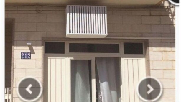 Un edificio con entrada de doble puerta, un letrero con el número 212 y una planta en maceta a la izquierda.