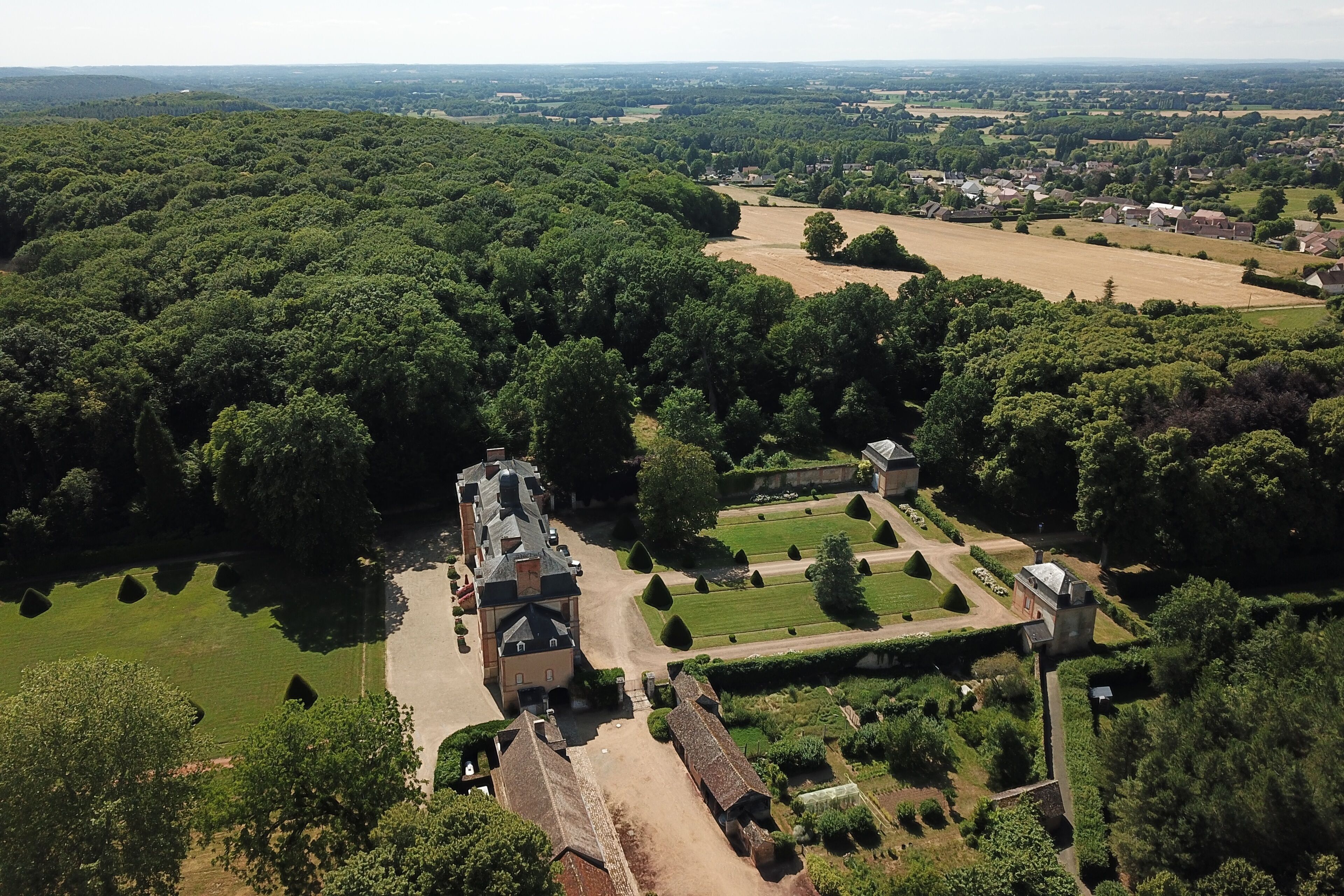 Luchtbeeld van een historisch landgoed met een groot herenhuis, formele tuinen en uitgestrekte velden.