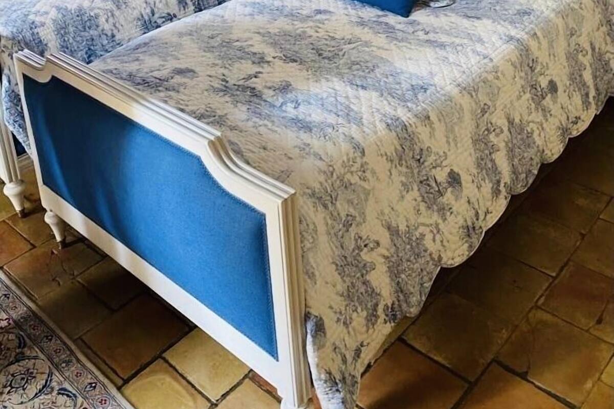 A double bed with a blue headboard and matching pillow, a white door with blue trim, and a patterned rug on the floor.