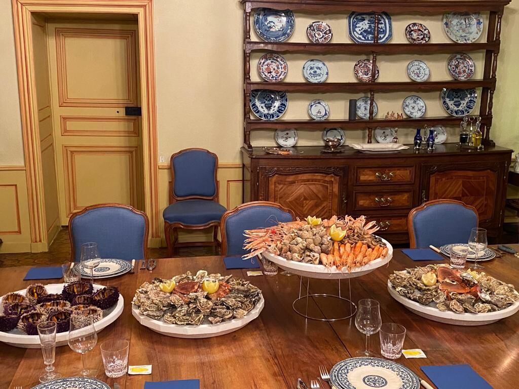 A dining table with seafood platters, blue chairs, and a china cabinet with plates.