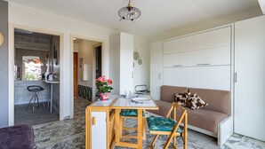 Una sala de estar moderna con un sofá, una mesa de comedor y una cocina visible a través de una puerta abierta.