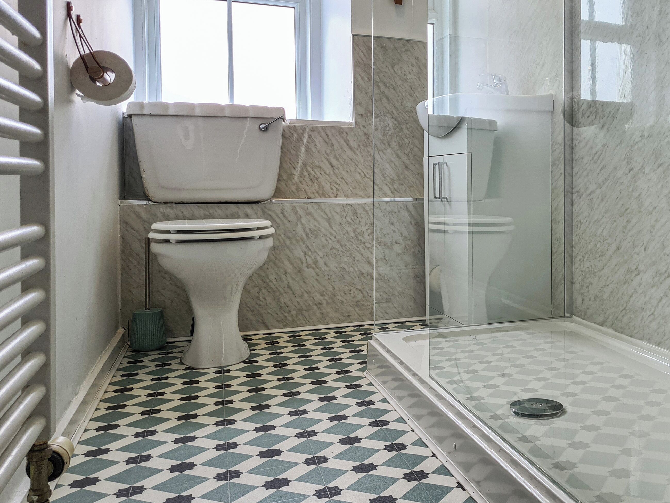 Une salle de bain équipée de toilettes, d’une douche et d’un carrelage décoratif.