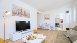 A modern living room with a flat-screen TV, a coffee table with snacks, a sofa, and a dining area with a table and chairs. - Hedera Estate, Hedera A38 (Dubrovnik)