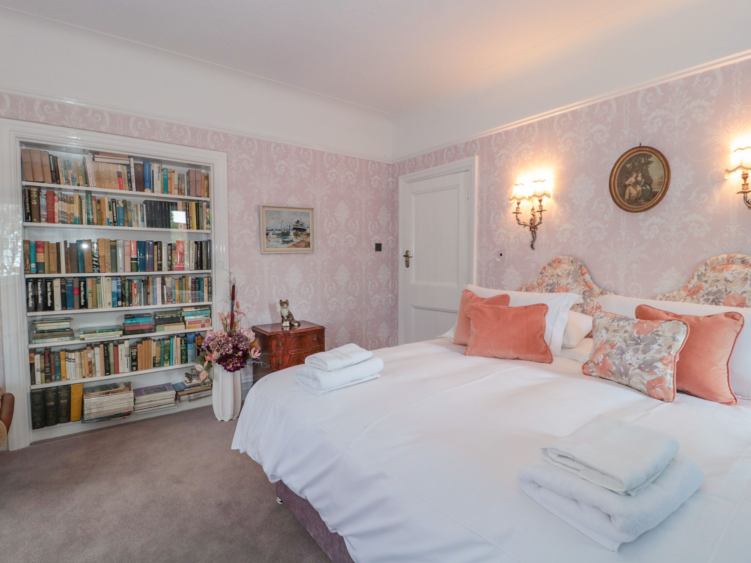 A bedroom with a large bed, a bookshelf, and a door.