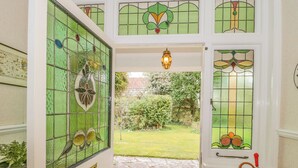 Uma porta com janelas de vitrais, um caminho de pedra e vista para o jardim.