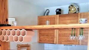 Een kleine keuken met houten aanrecht, een koffiezetapparaat, een spoelbak en twee krukken.
