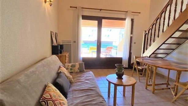 Een gezellige woonkamer met een bank, een kleine tafel en een trap naar een buitenruimte.