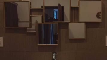 A bathroom with a rectangular sink, multiple mirrors, and a wall-mounted light fixture.