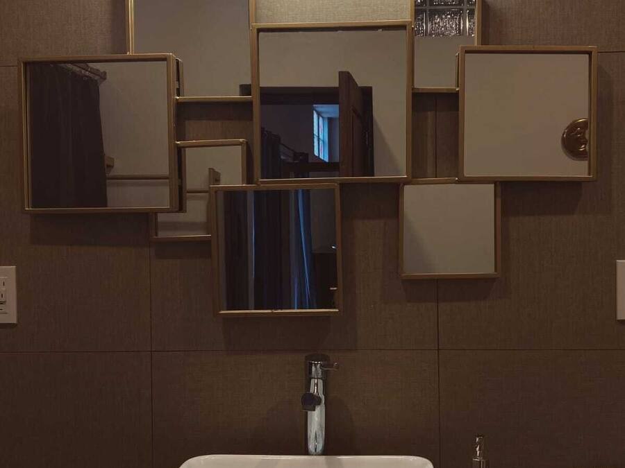 A bathroom with a rectangular sink, multiple mirrors, and a wall-mounted light fixture.