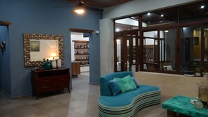 A living room with a blue sofa, a wooden cabinet, and a mirror on the wall. - Casona 13 Flechas (Mazatlán)