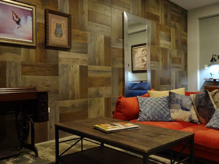 A living room with a wooden wall, a sofa with cushions, a coffee table, and a side table with a lamp.