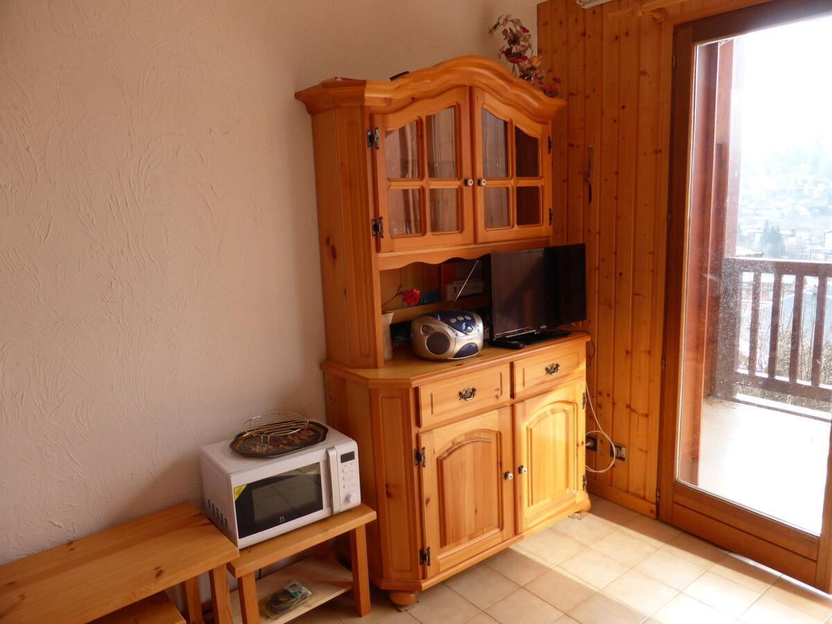Ein Holzkabinett mit einer Mikrowelle und einem Toaster auf einem Holztisch.