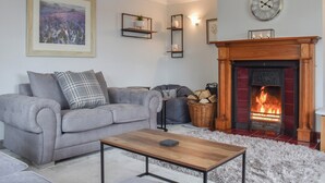 A living room with a grey sofa, a wooden coffee table, a fireplace, and a framed picture on the wall.