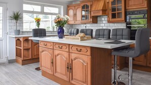 A modern kitchen with wooden cabinets, a central island, and bar stools.