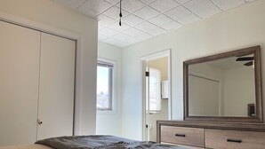 A bedroom with a bed, dresser, and a large mirror.