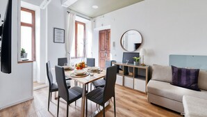 A dining area with a wooden table, black chairs, and a fruit bowl. There is a sofa and a TV on the wall. - [3 bathroom] Lovely Apartment in the Vatican, close to Castel Sant'Angelo (Roma)