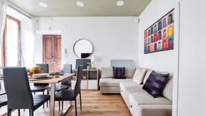 A modern living room with a sofa, a dining table with chairs, a TV, and a colorful artwork on the wall. - [3 bathroom] Lovely Apartment in the Vatican, close to Castel Sant'Angelo (Roma)