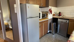 Cocina compacta equipada con refrigerador, microondas y lavavajillas.