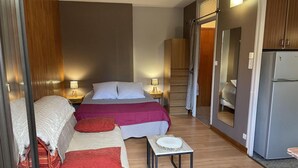 Una habitación de hotel con cama, sofá, mesita y refrigerador.